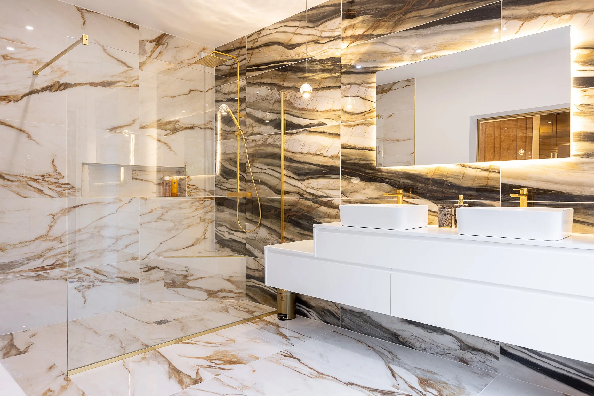 Salle de bain en marbre avec double vasque et robinetterie dorée