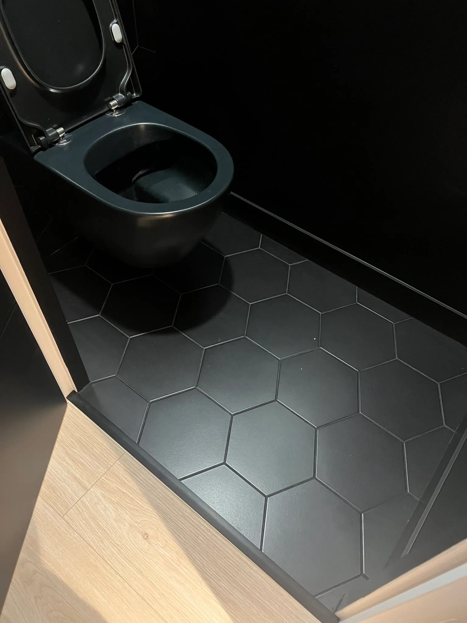 WC suspendu noir et carrelage hexagonal noir mat au sol